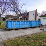 Blue,Dumpster,In,The,Driveway,Of,A,Residential,Home,That